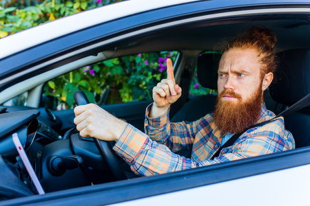 handsome redhaired ginger man with long beard going on trip during summer vacation on new carの写真素材