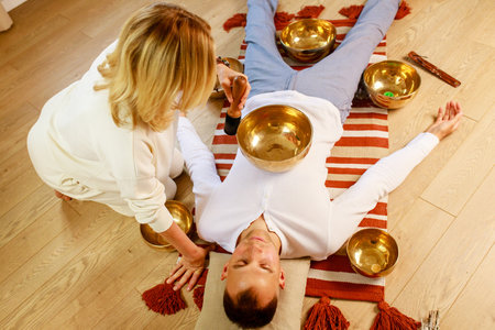 Woman playing on a tibetian singing bowl maling massage meditation for a manの写真素材