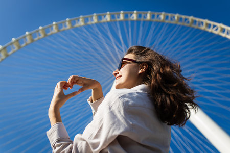 Happy woman tourist look at one of the largest Ferris Wheels in the World, located on Bluewaters island in Dubaiの写真素材