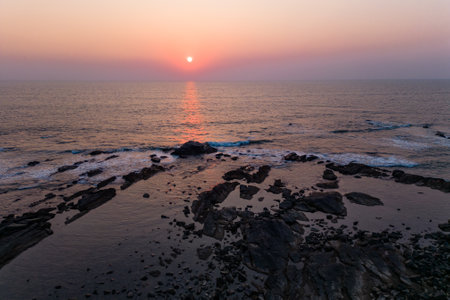 Aerial view of mountain peak and sea and sunset colorful sky from above from droneの写真素材