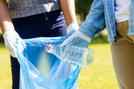 afro american volunteers collecting plastic trash at sunny day in summer parkの写真素材