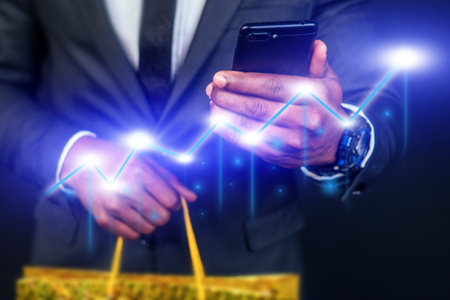 A man is holding a cell phone and wearing a suitの写真素材