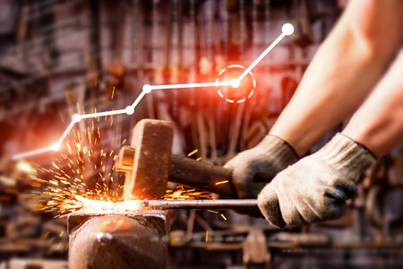 A person is hammering a piece of metal in front of a graph that shows a downward