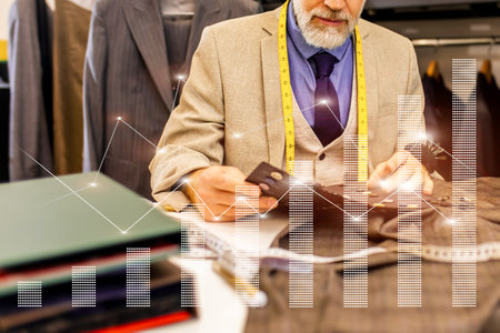 A man is sitting at a desk with a stack of papers and a cell phoneの写真素材