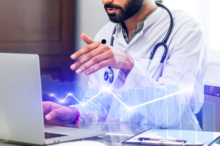A doctor is using a laptop computer while talking on the phoneの写真素材