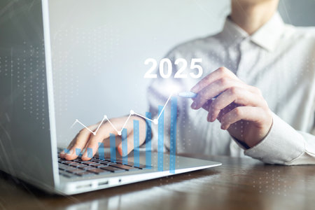 A person is typing on a laptop with a graph showing a line going up to 2025の写真素材