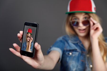 young pretty blonde women taking selfie on cell phone in studioの写真素材