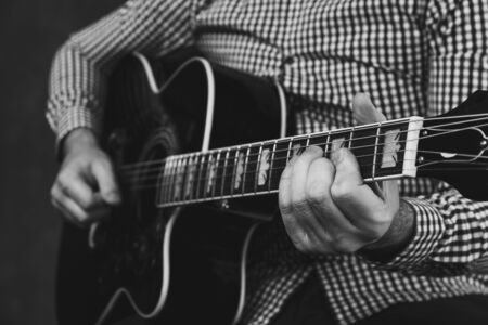 Man with acoustic guitar playing close up in studio