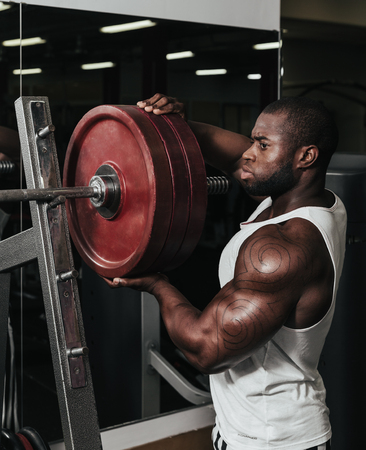 Weight training African doing bodybuilding in gym