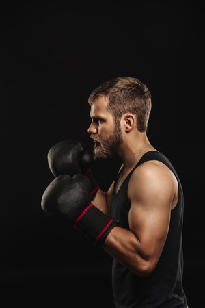 Athletic bearded boxer with gloves isolated on a dark backgroundの写真素材