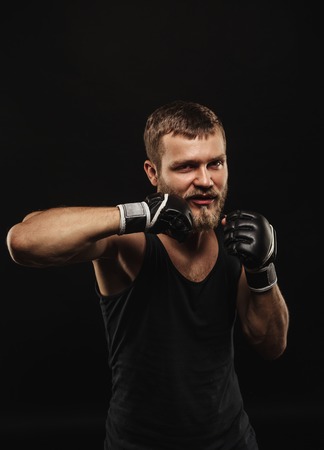 Athletic bearded boxer with gloves isolated on a dark backgroundの写真素材