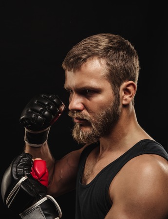 Athletic bearded boxer with gloves isolated on a dark backgroundの写真素材