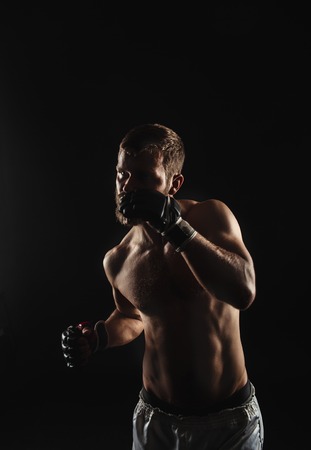 Athletic bearded boxer with gloves isolated on a dark background