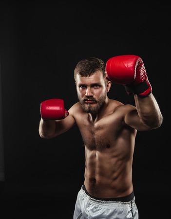 Athletic bearded boxer with gloves isolated on a dark backgroundの写真素材