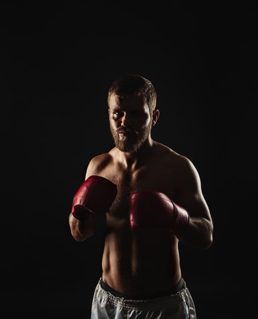 Athletic bearded boxer with gloves isolated on a dark backgroundの写真素材