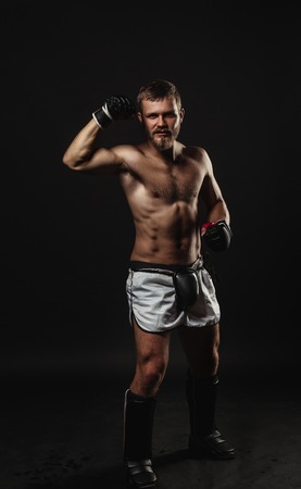 Athletic bearded boxer with gloves isolated on a dark backgroundの写真素材