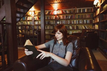 Beautiful female student in a university library reading book