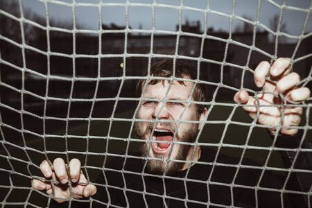 Energy furious bearded athlete screaming holding net outdoorの写真素材