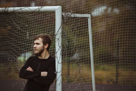 Male athlete resting on soccer field urban viewの写真素材