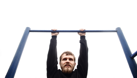 fitness, sport, exercising, training and lifestyle concept - young man doing pull ups on horizontal...