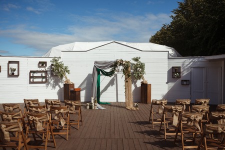 stunning wedding ceremony spot with wooden chairs, arc and flowersの写真素材