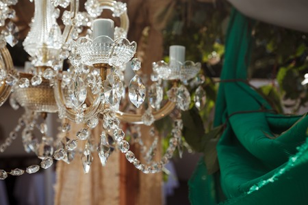 Beautiful crystal chandelier near green cloth wedding decorの写真素材