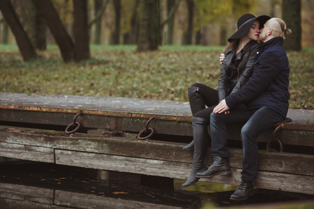 hipster guy kissing his girlfriend sitting on the pierの写真素材