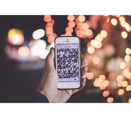 Hand holding an iphone, on bokeh background