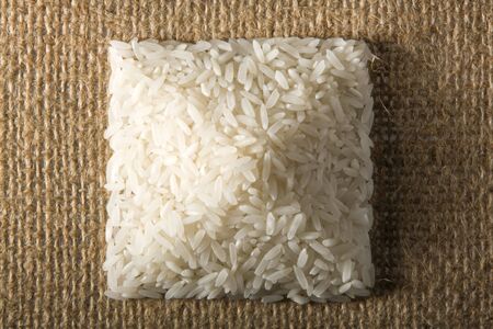 Stack of uncooked rice in the shape of pyramid photographed on burlap from the topの写真素材