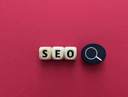 wooden cubes with magnifying glass, SEO concept on red background.