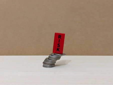 wooden cube on top of a tilted coin with the word Risk. Business finance concept.の写真素材