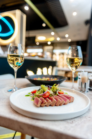 Tuna tataki salad with lettuce, cherry tomatoes and avocado on a marble table in a restaurant. High quality photoの写真素材