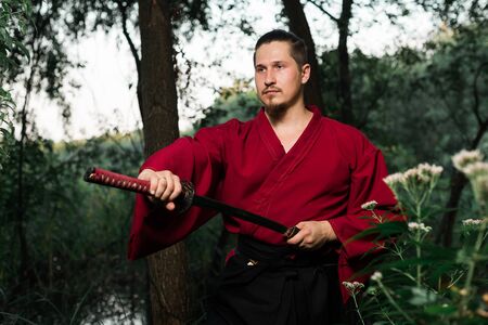 Man in ethnic samurai japanese clothing uniform with katana sword portraitの写真素材