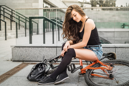 Colorful outdoor portrait of young pretty fashion model with bike. Young woman posing in summer.の写真素材