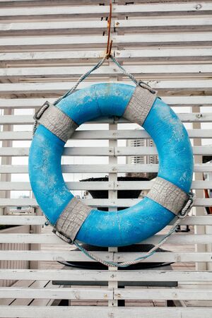 Blue lifebuoy hanging on a wood backgroundの写真素材