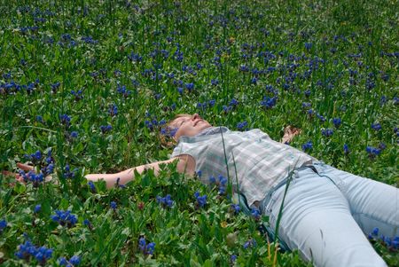   Relaxing girl on meadow in blue flowerの写真素材