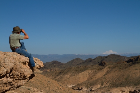 Tourist on the top of mountain massif watching landscape through binoculars  の写真素材