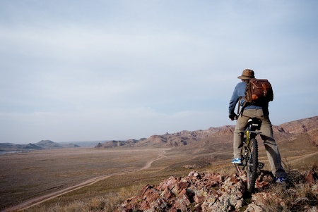 Bicyclist in hilly terrain looks at roadの写真素材