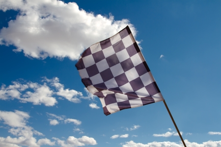 Checkered flag against the blue sky with cloudsの写真素材