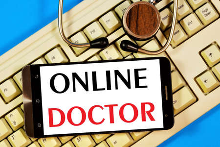 Online doctor-text inscription in a smartphone on the computer keyboard. News information, consultation, appointment with a specialist doctor.の写真素材
