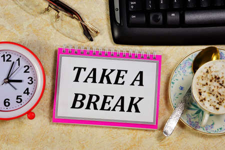 Break time - a text message in the planning Notepad on the background of the clock. Take a break to relax or enjoy a healthy drink.の写真素材