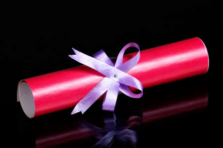 Scroll sheet in roll and ribbon with bow. Red diploma is a document of a graduate student, a certificate of graduation from a University, College and obtaining the title, academic degree.の写真素材