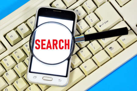Search - the user's query. The inscription on the smartphone screen on the computer keyboard.