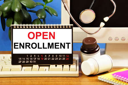 Open enrollment. Text inscription in the calendar on the background of medicines and a stethoscope....