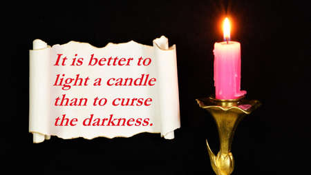It is better to light a candle than to curse the darkness. The text of the motivation for solving problems on a vintage scroll.の写真素材