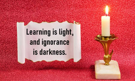 Learning is light, and ignorance is darkness. The text of a wise thought on a vintage scroll.の写真素材