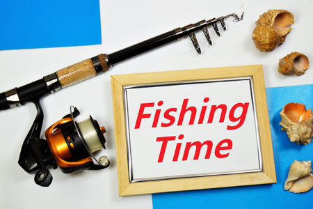 Fishing time. The inscription on the background of spinning and seashells. Sports recreation, in nature. Entertainment on the sea, lake or river.の写真素材