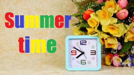 Summer time. The inscription in multicolored letters on the background of garden flowers and clocks. The warmest time of the year.の写真素材