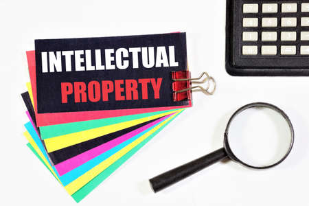 Intellectual property. The inscription on the stickers, on the background of a magnifying glass and a calculator. The exclusive right of authors to the result of their activity, enshrined by law.の写真素材