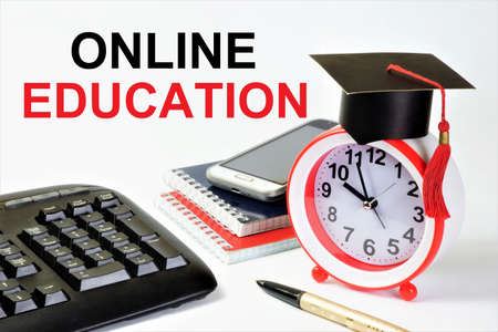 online education. Lettering on the background of textbooks, keyboard and planning clock. Distance training with the help of computer telecommunication technologies.の写真素材